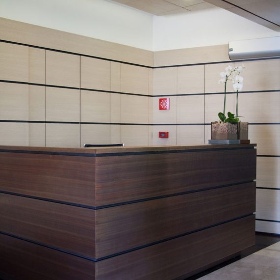 Bancone reception con boiseire in laminato rovere e rame