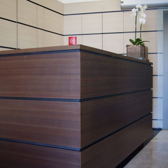 Bancone reception con boiseire in laminato rovere e rame